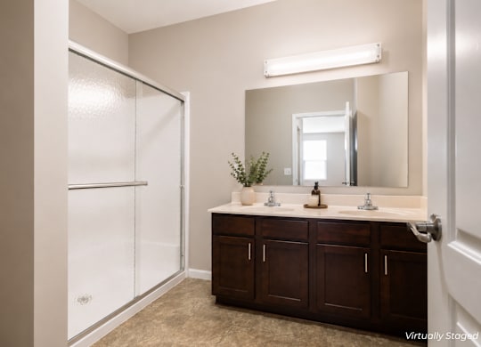 A bathroom with a brown vanity and a white shower.