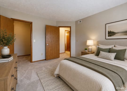 A bedroom with a large bed and a painting on the wall.