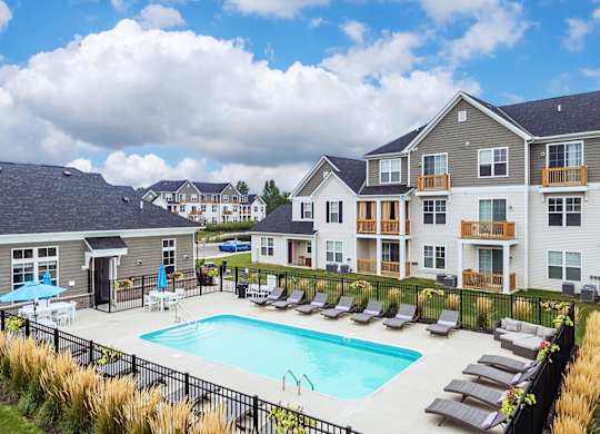 a swimming pool with lounge chairs in front of apartment buildings