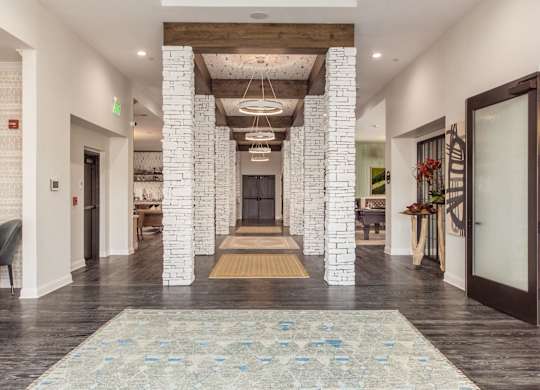 A hallway with a rug in the middle and a fireplace on the left.