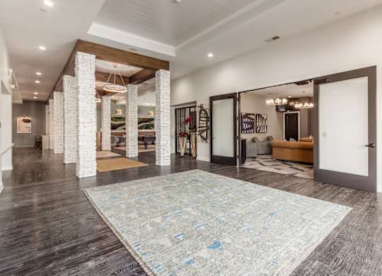 A large room with a rug on the floor and a staircase on the left side.