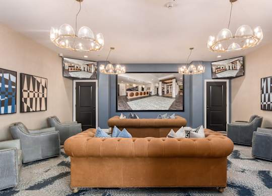 A living room with a brown sofa and grey chairs.