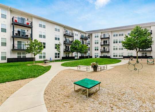 A playground area with a green table and swings in front of apartment buildings.