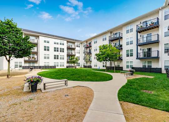 A sunny day at a residential complex with a walkway and green grass.