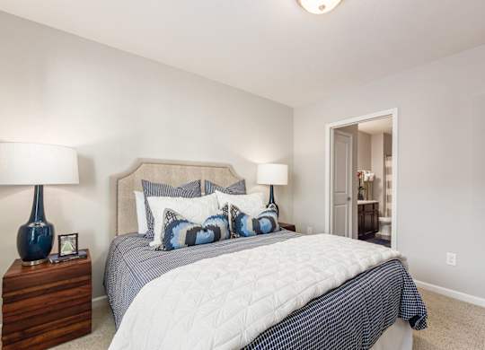 A bedroom with a bed, two lamps, and a nightstand.