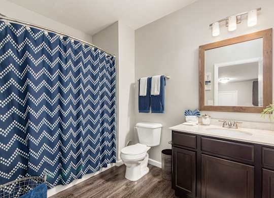 A bathroom with a white toilet, a sink, and a blue and white shower curtain.