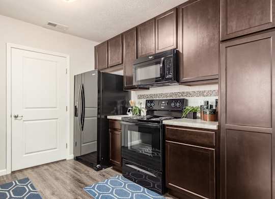 A kitchen with brown cabinets and black appliances.