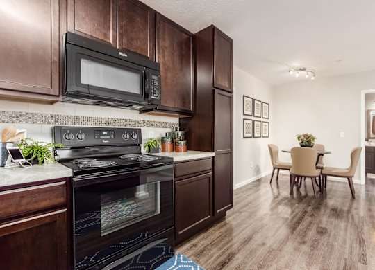 A kitchen with dark wood cabinets and a black stove top oven.
