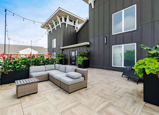 A patio with a wicker sofa and a table with a planter on it.