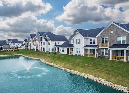 a fountain in the middle of a pond in front of houses