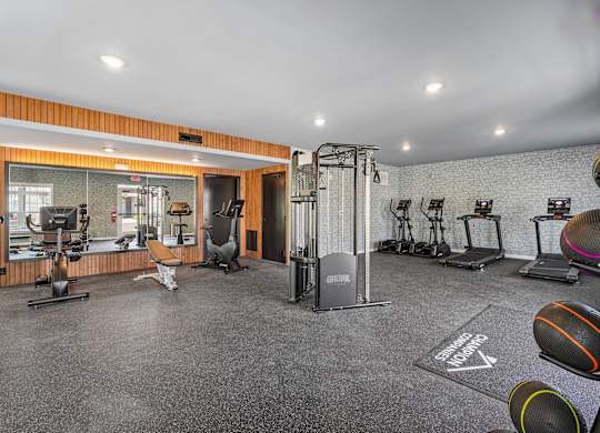 A gym with a variety of equipment including treadmills, weights, and exercise machines.