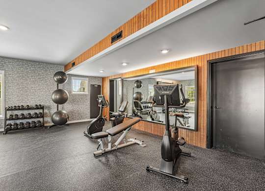 A gym with a variety of equipment including a weight bench, a leg press machine, and a squat rack.