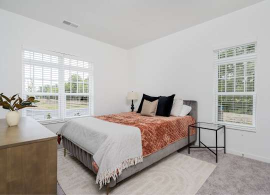 A bedroom with a bed, nightstand, and window.