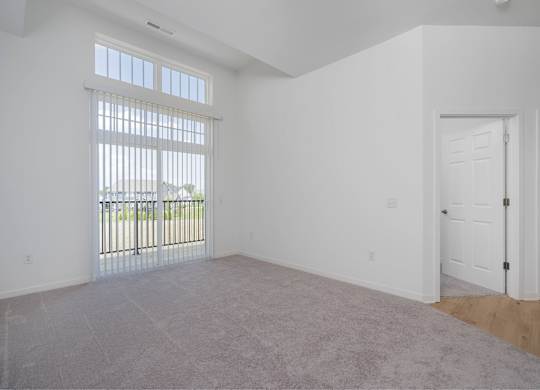 A room with a carpeted floor and a sliding glass door.