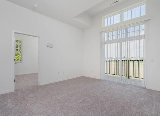 A large empty room with a window and a door.