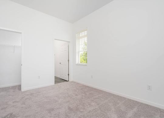 A room with a carpeted floor and two doors.