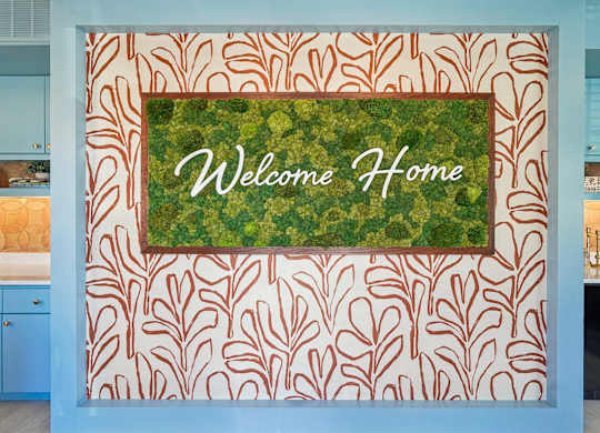 A wall with a leaf pattern and a sign that says Welcome Home.
