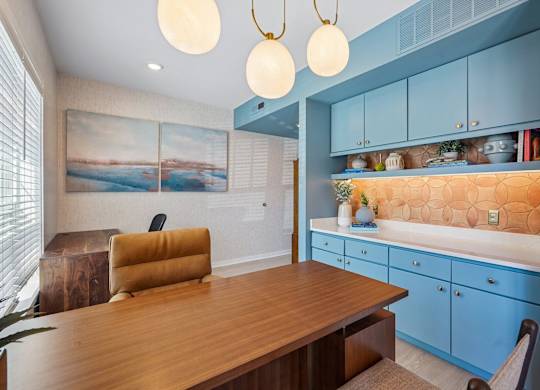 A room with a wooden table and blue cabinets.