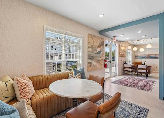 A living room with a round table surrounded by chairs and a large window.