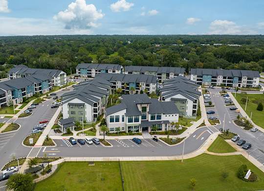 A large, modern housing complex with a parking lot in front.