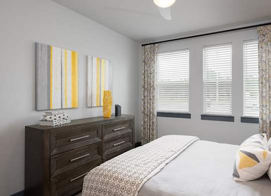 A bedroom with a bed, dresser, and two wall art pieces.