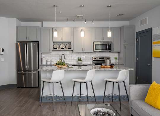 A modern kitchen with a bar stool and a dining table.