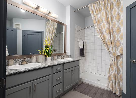 A bathroom with a sink, mirror, and shower.