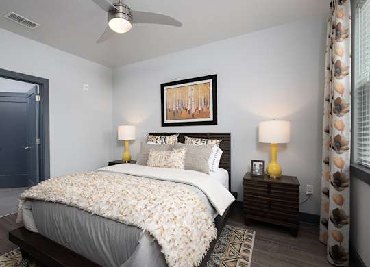 A bedroom with a bed, nightstands, and a ceiling fan.