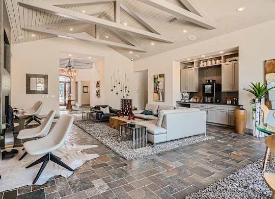 A modern living room with a stone floor and a high ceiling.