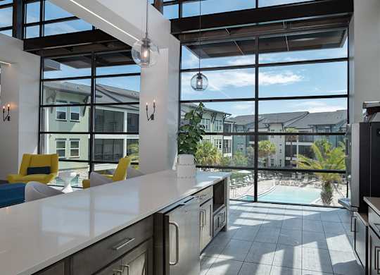 A kitchen with a view of the pool and houses outside.