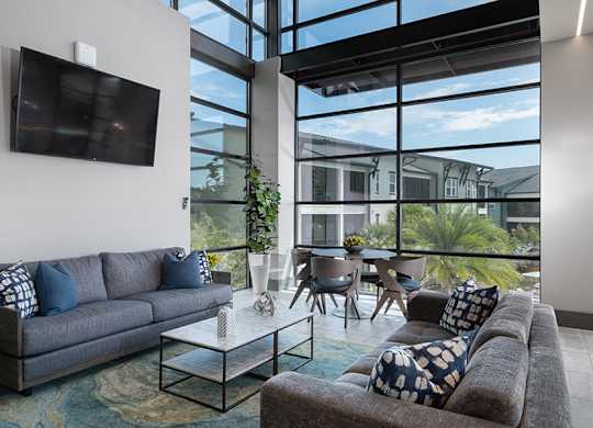 A living room with a grey couch and a flat screen TV mounted on the wall.