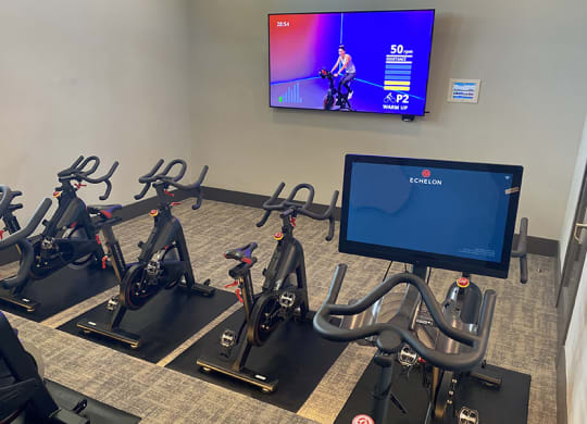 a row of exercise bikes in front of a tv