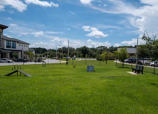 A park with a green sign in the middle of a grassy area.