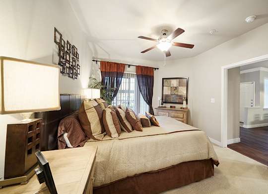 A bedroom with a bed, a ceiling fan, and a window with curtains.