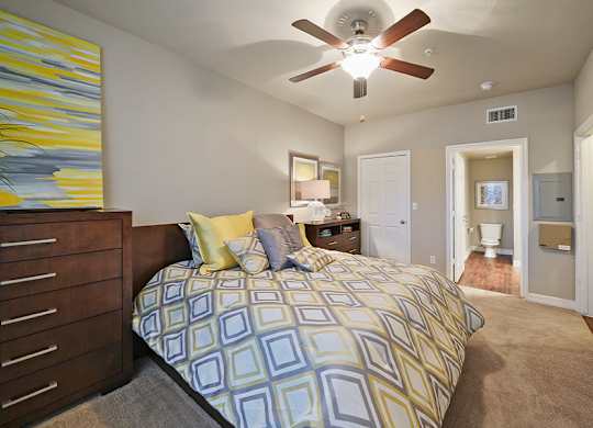 A bedroom with a bed, dresser, mirror, and a painting on the wall.
