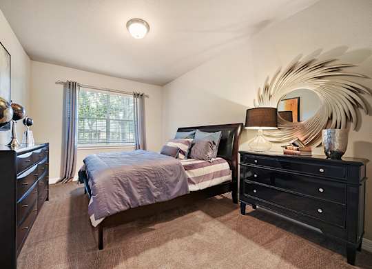 A bedroom with a bed, dresser, and mirror.