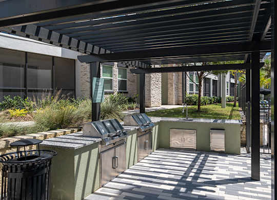 A row of green trash bins are lined up under a black awning.