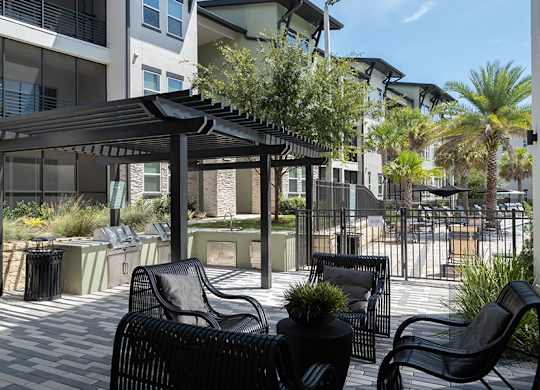 A patio with black chairs and a table under a black canopy.