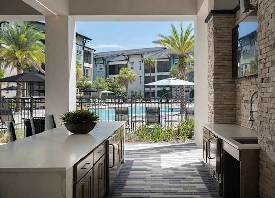 A kitchen with a view of a pool and palm trees.