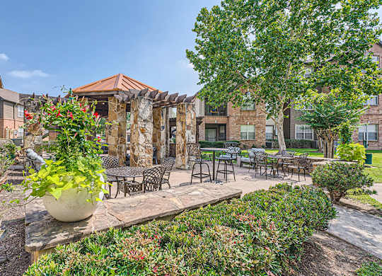 A patio area with a table and chairs surrounded by green plants.