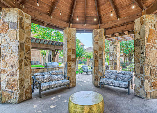 Stone pillars support a roof over a seating area.