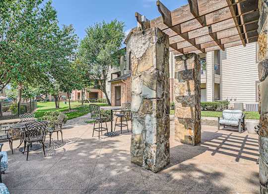 A patio with a table and chairs under a wooden pergola.