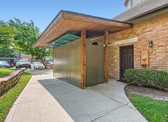 A brick house with a wooden porch and a green bush.