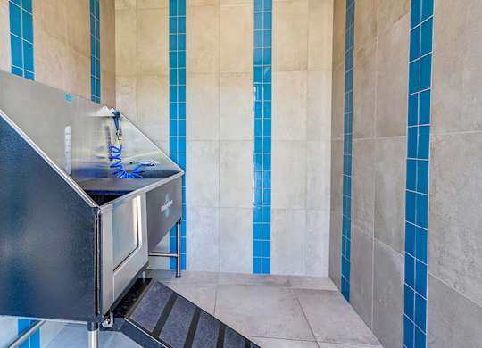 A black stainless steel sink in a bathroom with blue tiles.