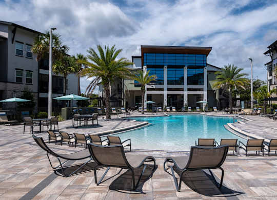 A pool surrounded by chairs and palm trees.