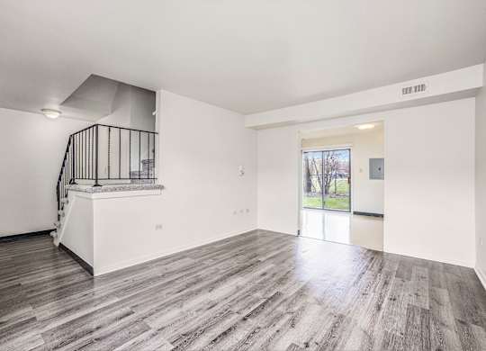 A spacious room with a staircase and a view of the outdoors.