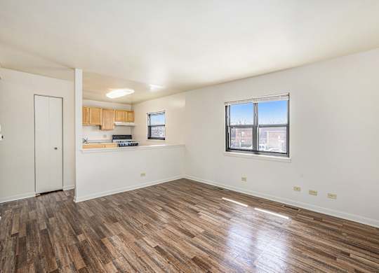 A room with wooden flooring and a window overlooking a building.