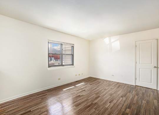 A room with a wooden floor and a window.