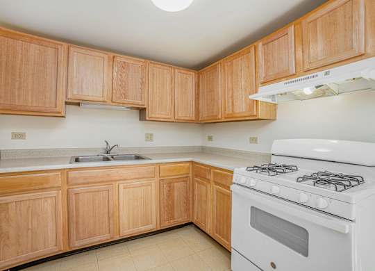 A kitchen with wooden cabinets and a white stove.