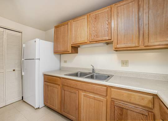 A kitchen with wooden cabinets and a white refrigerator.